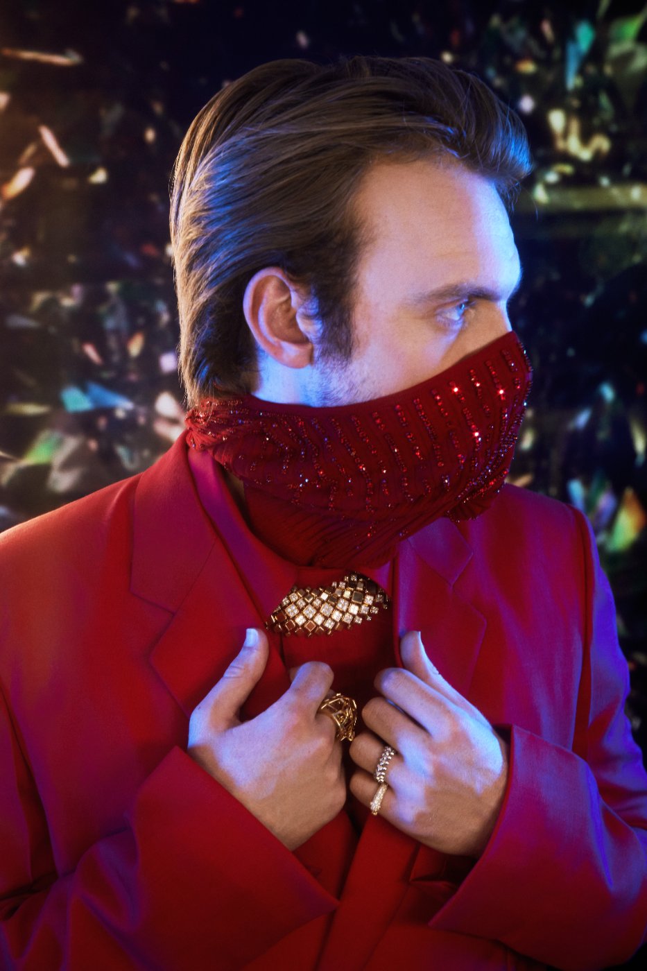 A guest in a red beaded mask and red suit with a Cartier brooch