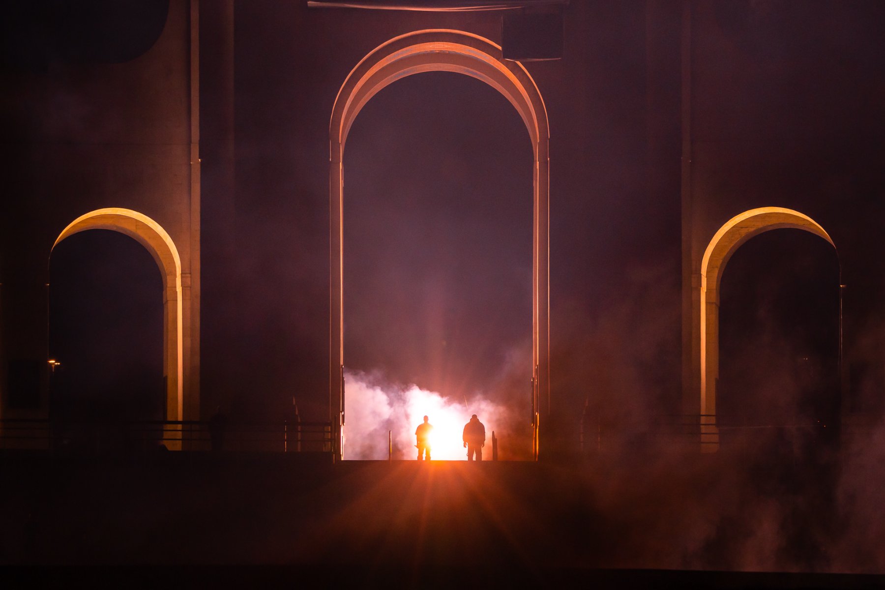 The Coliseum arches silhouetted, a flare of light bursting through