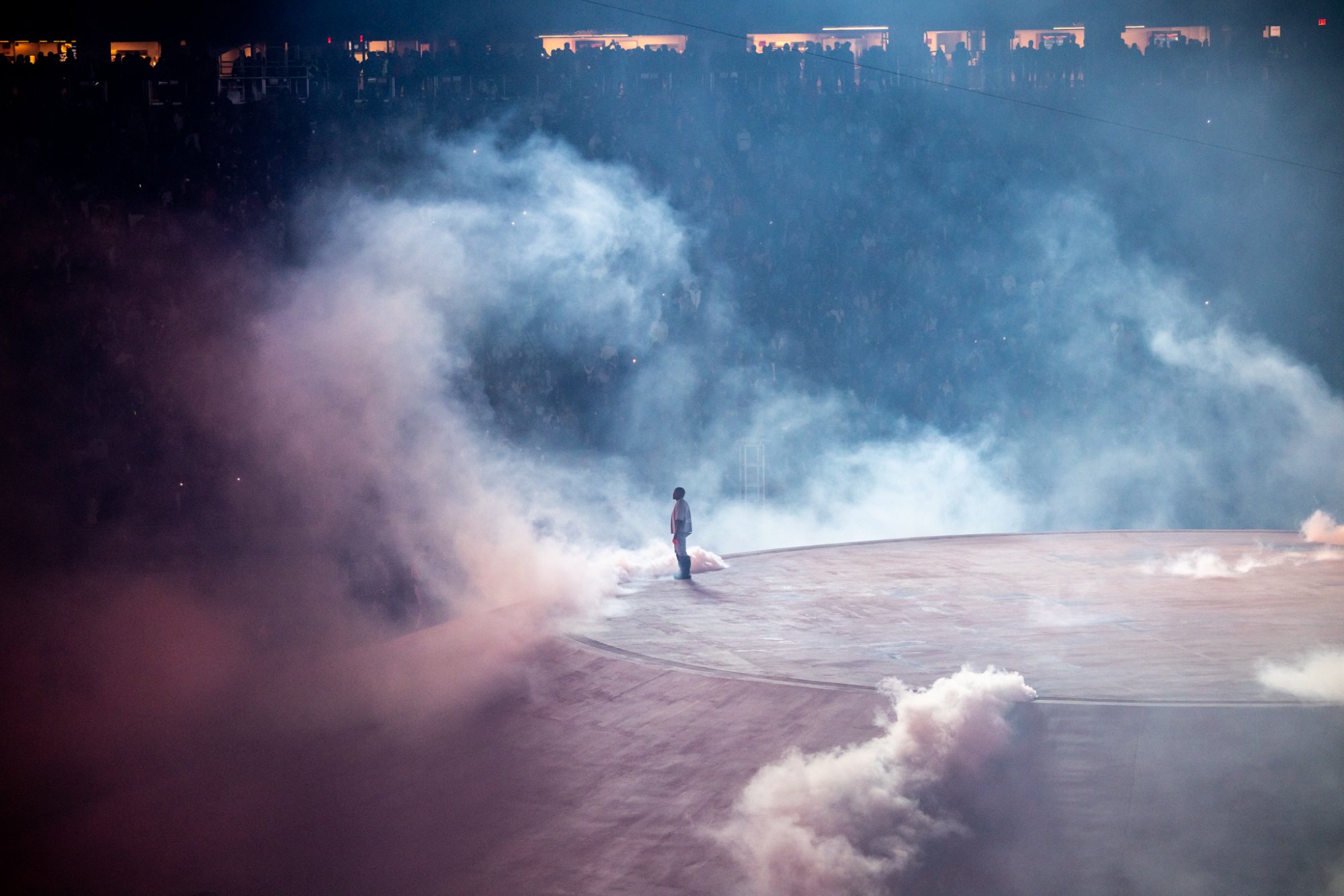 A lone figure stands on the edge of the concrete Mound as smoke fills the Coliseum