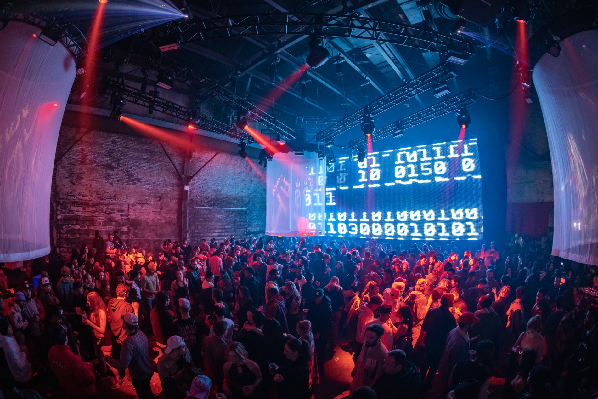 The crowd under a giant LED wall of streaming binary code