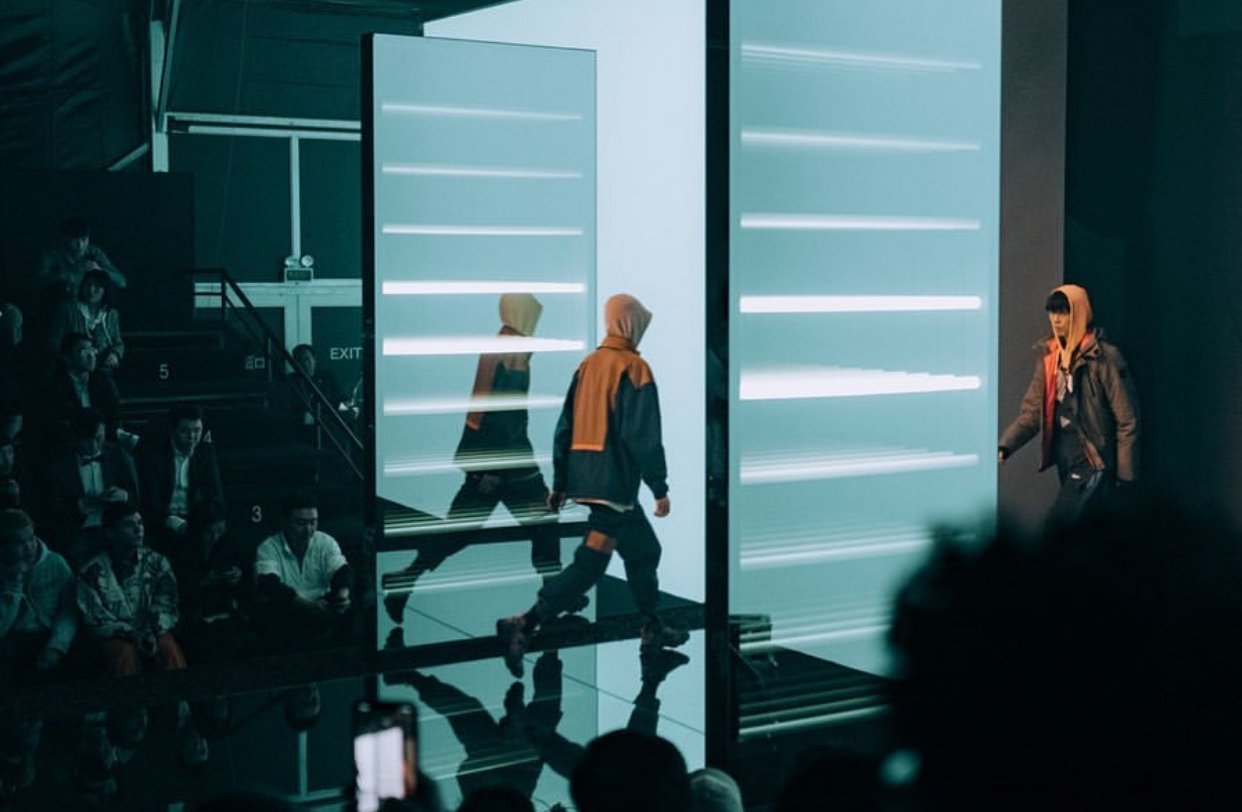 Models pass through a lit two-way mirror archway