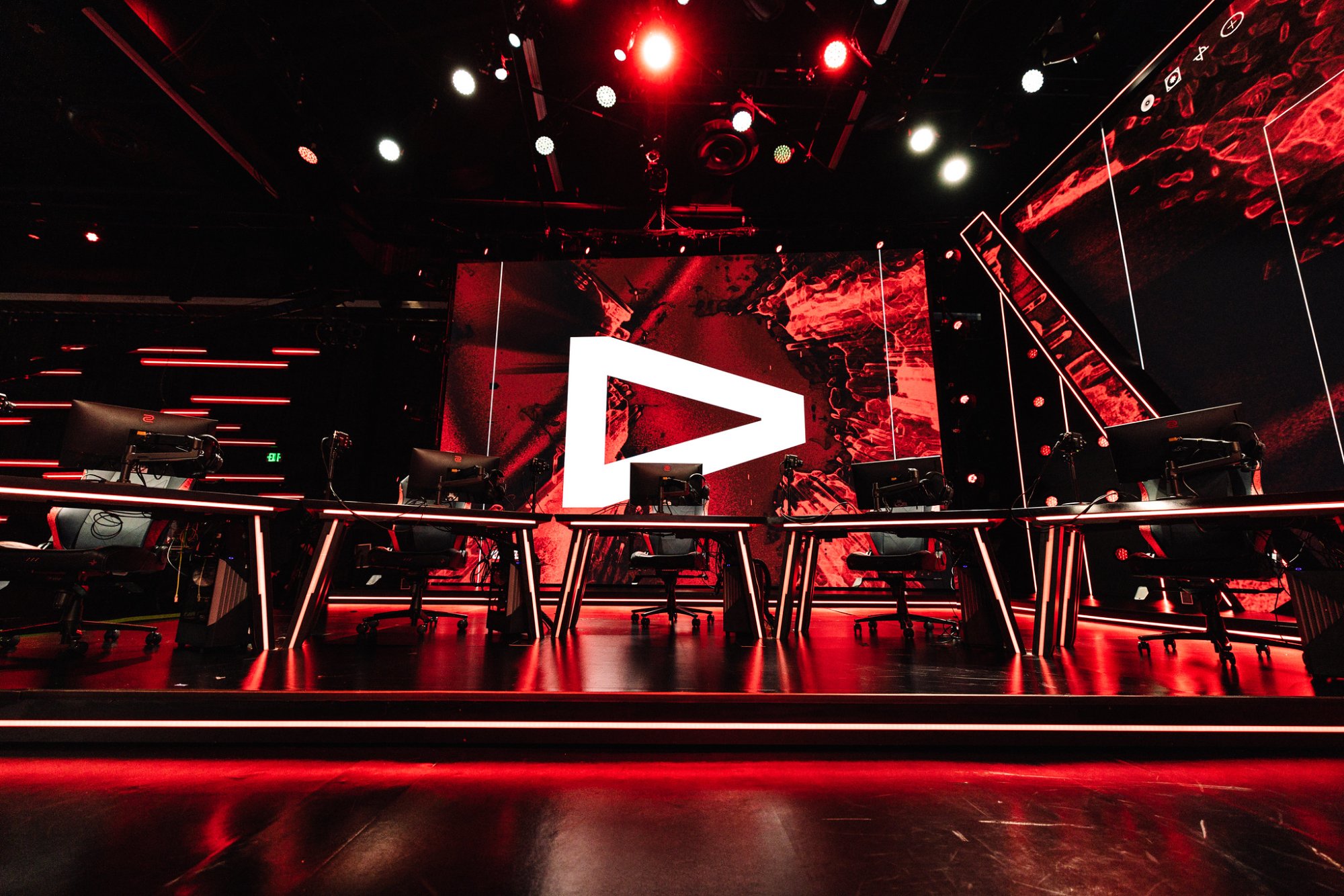 The Valorant stage configuration, player desks under a white play-button screen in red