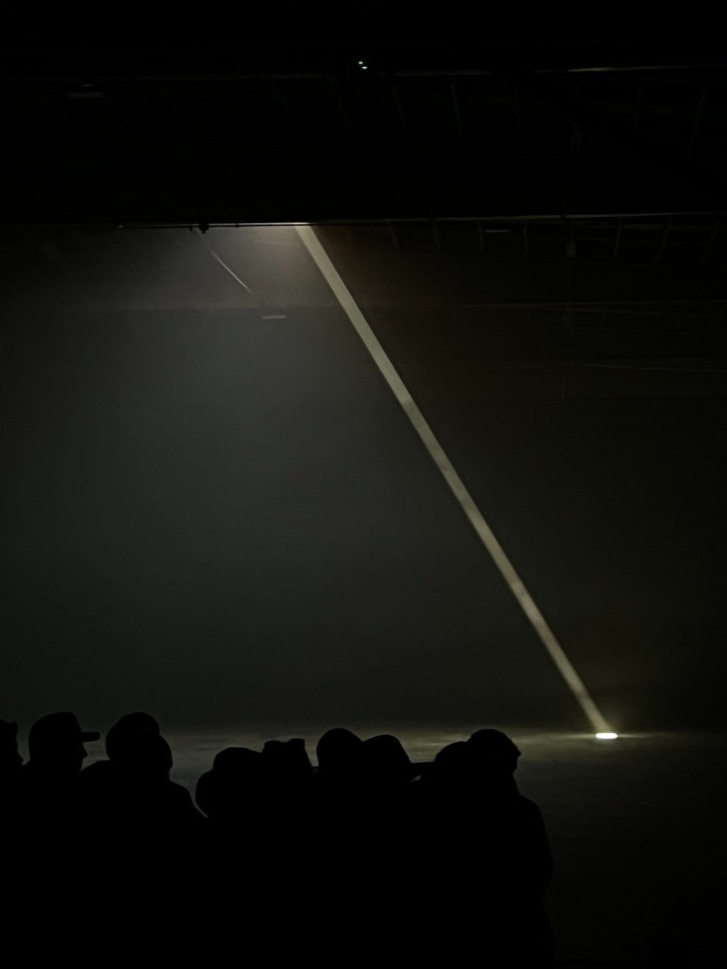 A single diagonal beam of light over a silhouetted crowd