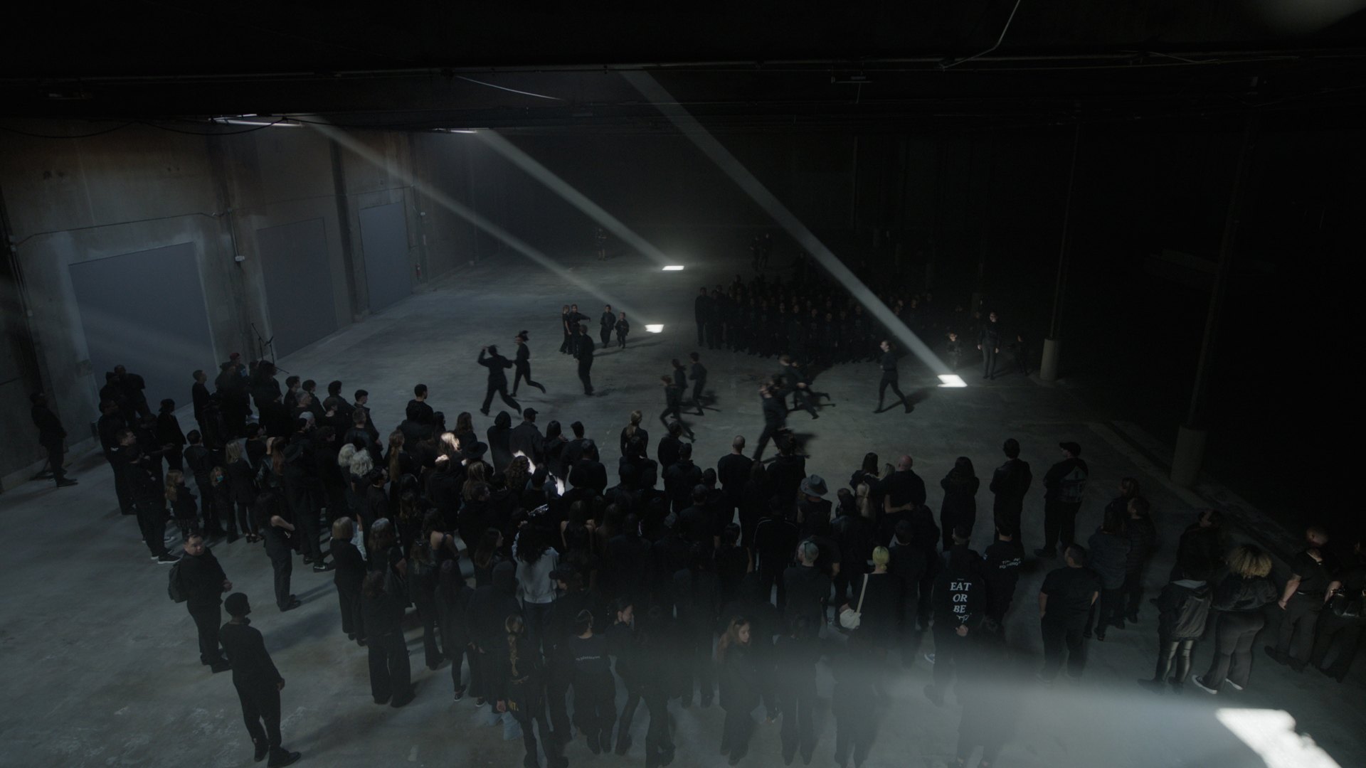 Overhead of the congregation ringed around performers under crossing beams